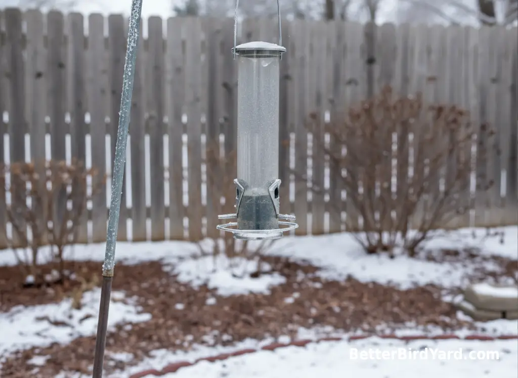 An empty clean feeder hangs from a pole after winter feeding has been paused.